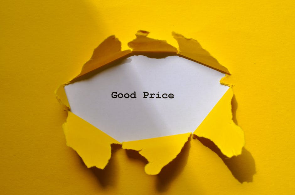 A close-up of a piece of torn yellow paper revealing a white note with the words 'Good Price' typed in black text. The torn paper edges are uneven and curled, creating a jagged frame around the note. The background is a solid yellow surface, and the lighting casts distinct shadows from the torn edges onto the background. This image illustrates concepts related to affordable house removals and packing services, with a focus on transparent pricing for home relocation, as offered by Man with Van Hanworth, a professional company specializing in removals and furniture transport within the moving logistics process.