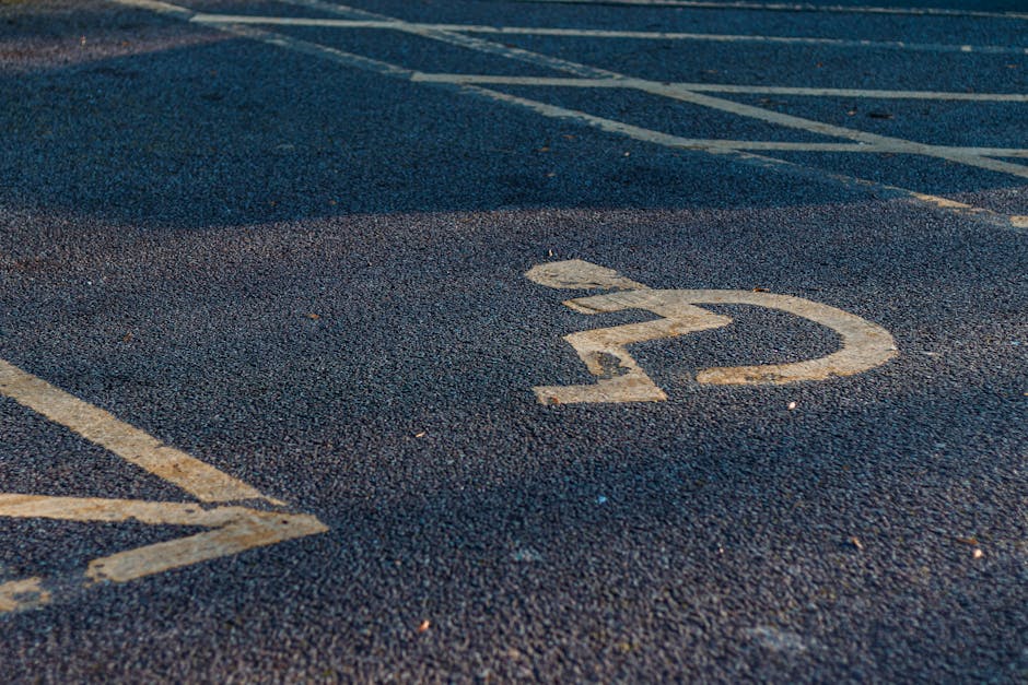 Close-up view of an outdoor parking space surface made of dark asphalt, featuring a faded white-painted number '22' marking. There are additional white parking lines neighbouring the numbered space, which is intended for vehicle parking related to house removals or relocation services. The image captures the surface with minor cracks and scattered small debris, indicative of an external environment typical for home moving logistics. This parking space could be used for loading or unloading furniture and boxes during a move managed by Man with Van Hanworth, aligning with guidance on parking, timing, and access for house removals at Hanworth. The overall scene emphasizes the importance of understanding parking arrangements in relocation planning, particularly for efficient furniture transport and packing and moving operations.